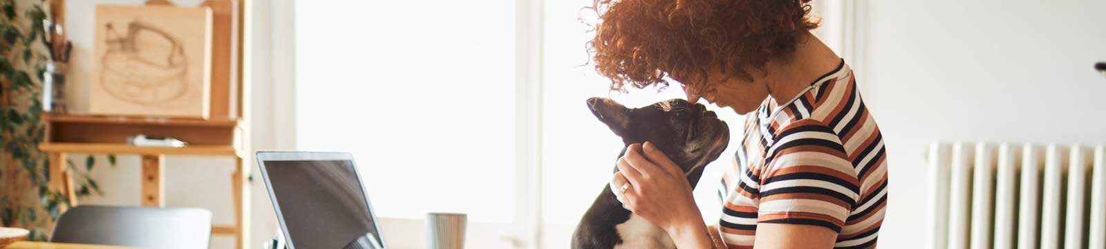 Lady playing with her dog while using a laptop computer